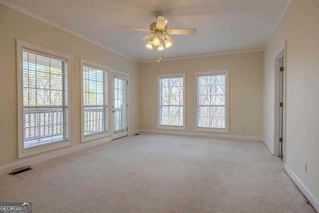 empty room with visible vents, crown molding, a ceiling fan, and light carpet
