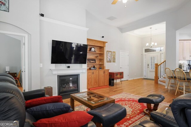 123 Heritage Pointe, Woodstock, GA 30189 - living area featuring a chandelier, a towering ceiling, light wood-type flooring, a glass covered fireplace, and baseboards