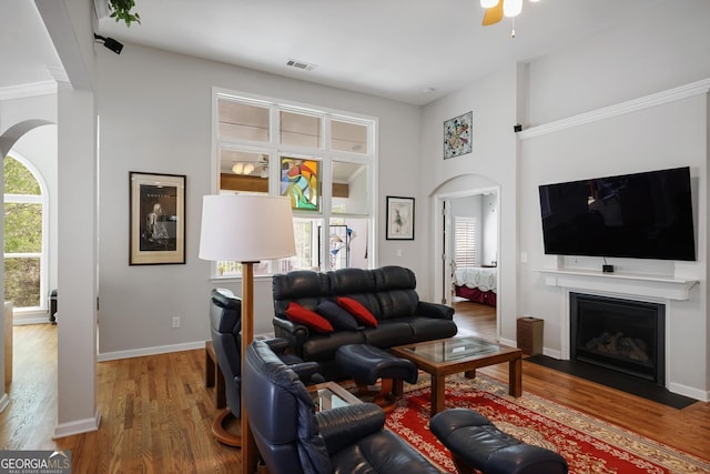 123 Heritage Pointe, Woodstock, GA 30189 - living area with wood finished floors, arched walkways, a fireplace with flush hearth, ceiling fan, and a towering ceiling