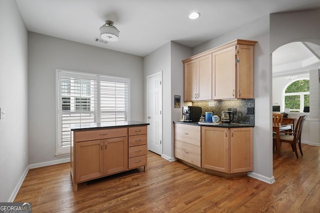 123 Heritage Pointe, Woodstock, GA 30189 - kitchen featuring dark countertops, arched walkways, light wood-style flooring, tasteful backsplash, and baseboards