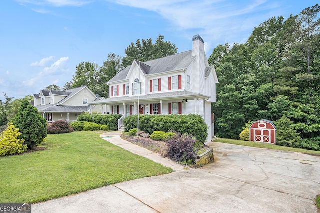 view of front of property with a storage shed, a porch, an outdoor structure, a front yard, and a chimney