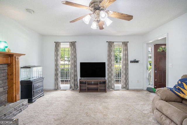 carpeted living area featuring healthy amount of natural light, baseboards, a ceiling fan, and a brick fireplace