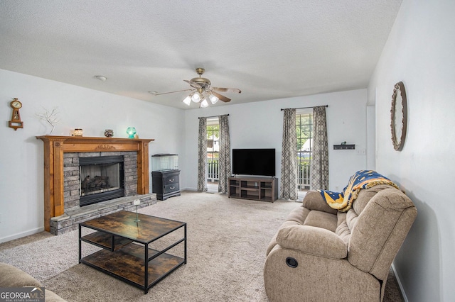 living area featuring carpet, a ceiling fan, a textured ceiling, a stone fireplace, and baseboards