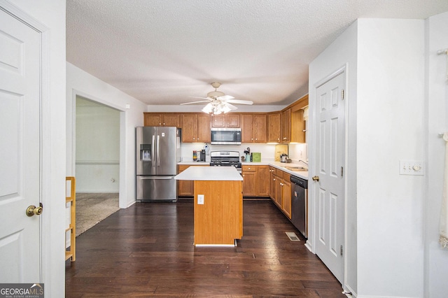 kitchen with stainless steel appliances, a kitchen island, light countertops, a ceiling fan, and dark wood-style flooring