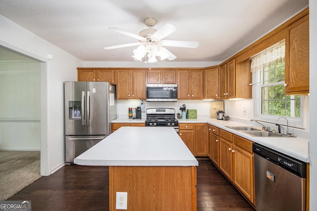 kitchen with stainless steel appliances, a sink, light countertops, a ceiling fan, and a kitchen island