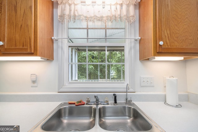 kitchen view of a sink, brown cabinets, and light countertops