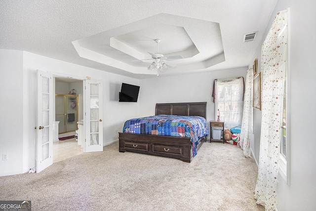 bedroom featuring french doors, carpet, a raised ceiling, and ensuite bathroom