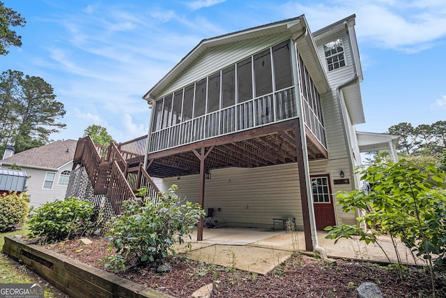 rear view of property with a sunroom, a patio, and stairs