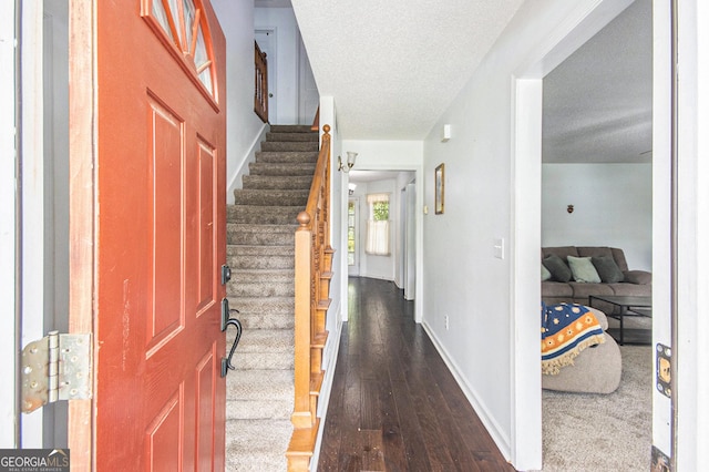 entryway featuring stairway, wood-type flooring, a textured ceiling, and baseboards
