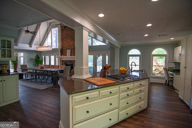 kitchen with green cabinetry, dark wood-style flooring, a brick fireplace, crown molding, and a kitchen island