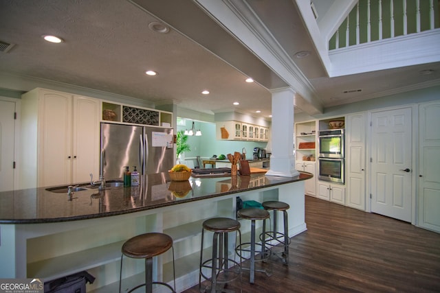 kitchen with open shelves, stainless steel appliances, dark wood finished floors, ornamental molding, and decorative columns