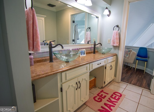 bathroom with crown molding, tile patterned flooring, a sink, and double vanity