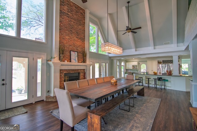dining area with a fireplace, wood finished floors, high vaulted ceiling, and ceiling fan