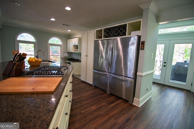 kitchen with dark wood finished floors, crown molding, appliances with stainless steel finishes, and a sink