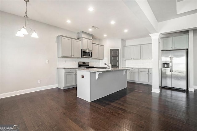 kitchen featuring gray cabinets, backsplash, stainless steel appliances, and a breakfast bar area