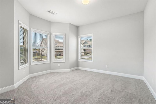empty room featuring baseboards, visible vents, and carpet flooring