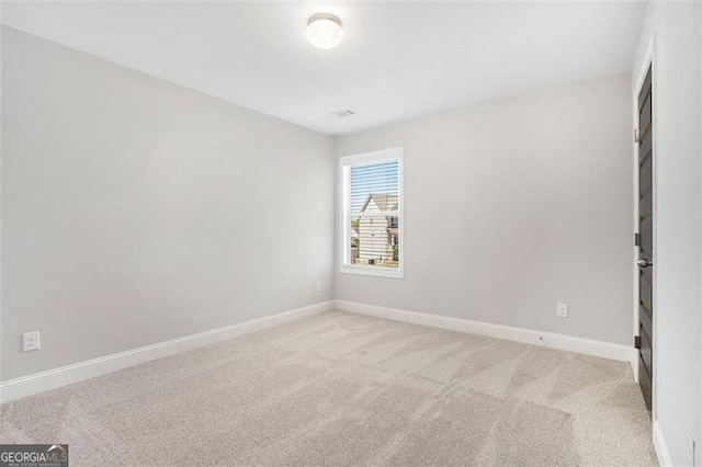 spare room with baseboards and light colored carpet
