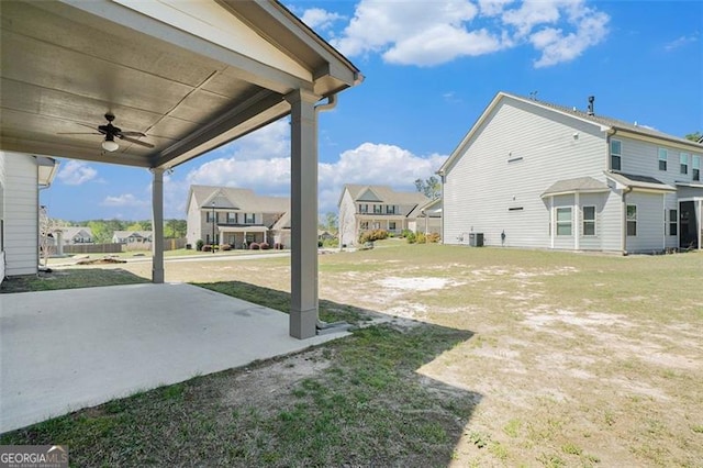 view of yard with a ceiling fan, central air condition unit, a residential view, and a patio
