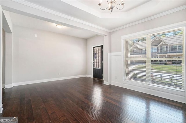 unfurnished room featuring an inviting chandelier, a tray ceiling, crown molding, baseboards, and hardwood / wood-style flooring