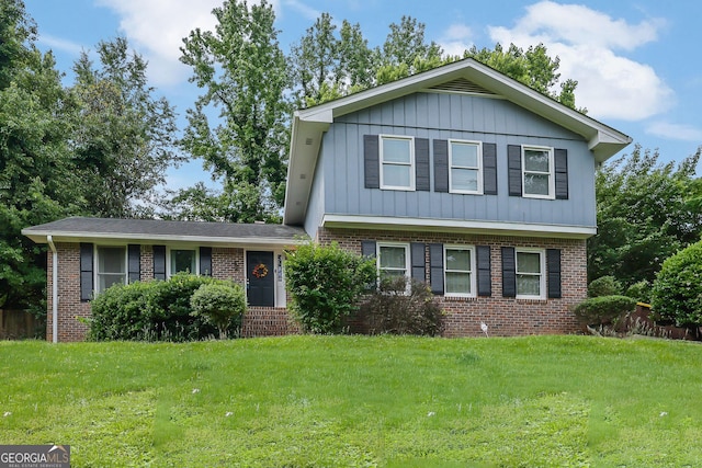 tri-level home with brick siding, a front yard, and board and batten siding