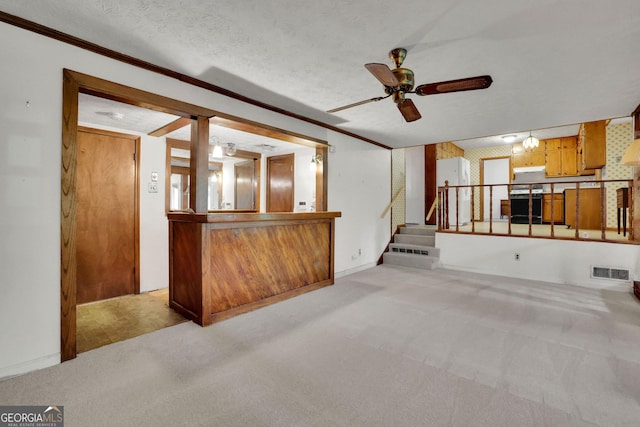 unfurnished living room featuring light colored carpet, a ceiling fan, stairway, ornamental molding, and a textured ceiling