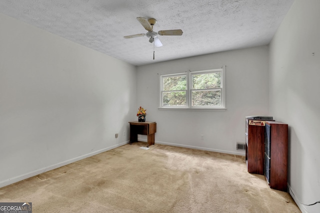 unfurnished room featuring a textured ceiling, ceiling fan, carpet flooring, and baseboards