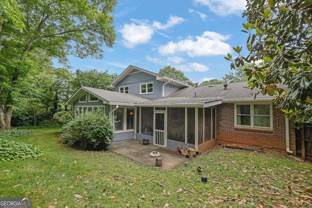 rear view of property featuring a sunroom, a lawn, a patio, roof with shingles, and brick siding