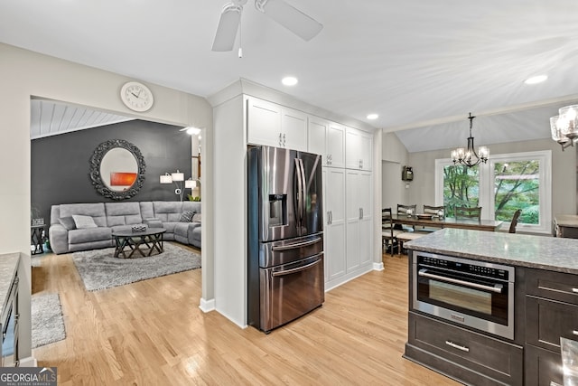 kitchen featuring white cabinets, stainless steel appliances, ceiling fan with notable chandelier, and light wood-style flooring