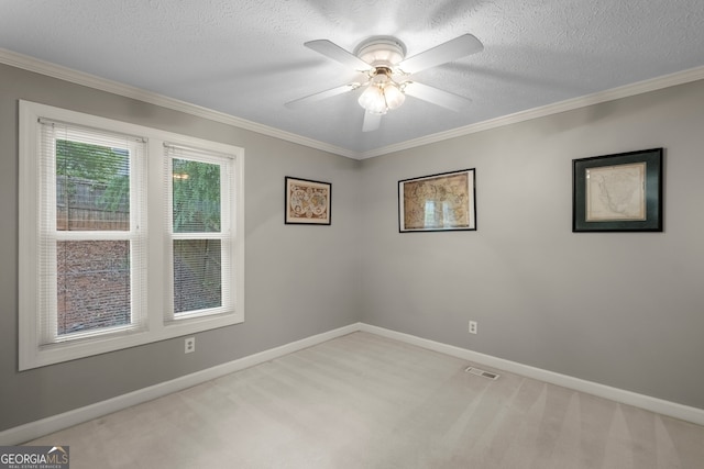 carpeted empty room featuring a textured ceiling, a ceiling fan, crown molding, and baseboards