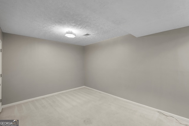 unfurnished room with a textured ceiling, visible vents, light colored carpet, and baseboards