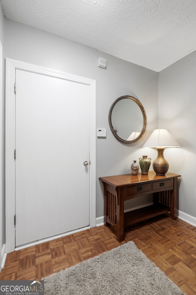 foyer entrance with a textured ceiling and baseboards