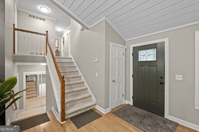 entrance foyer with visible vents, light wood-type flooring, baseboards, stairway, and crown molding