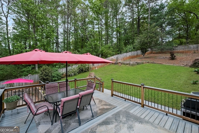 deck with outdoor dining space, a fenced backyard, and a yard