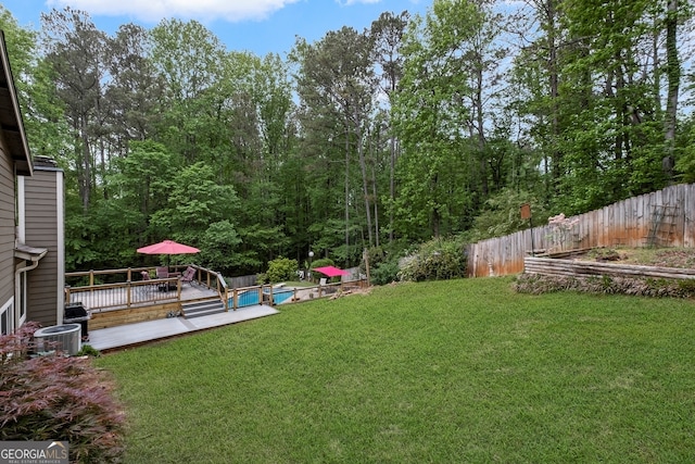 view of yard featuring a wooden deck, a fenced in pool, fence private yard, and central AC unit