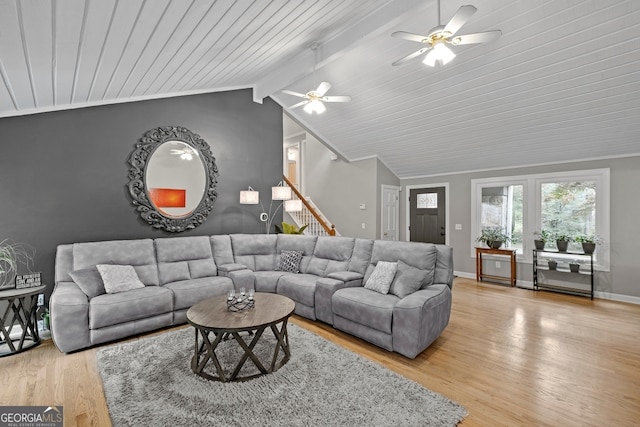 living room with light wood-style flooring, stairway, baseboards, a ceiling fan, and vaulted ceiling with beams