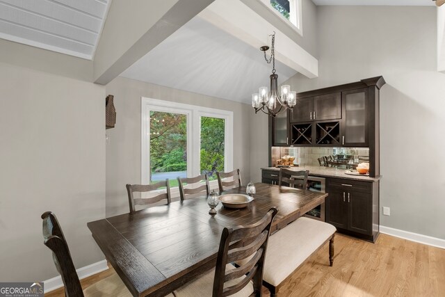 dining space featuring lofted ceiling with beams, plenty of natural light, light wood finished floors, and wet bar