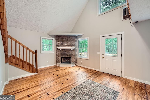 unfurnished living room featuring a fireplace, a textured ceiling, hardwood / wood-style flooring, and high vaulted ceiling