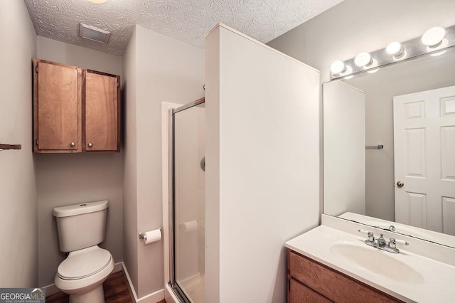bathroom with toilet, vanity, visible vents, a stall shower, and a textured ceiling