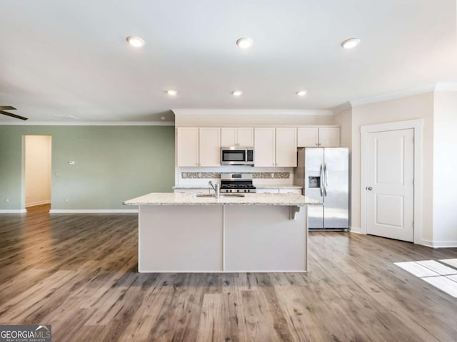 2959 Rambler Dr, Loganville, GA 30052 - kitchen with baseboards, appliances with stainless steel finishes, crown molding, and a center island with sink