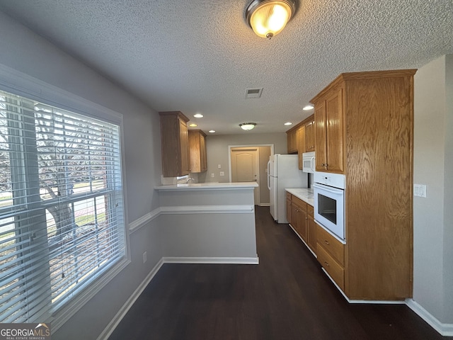 1365 Jubilee Ln, Mcdonough, GA 30253 - kitchen featuring dark wood-style floors, a textured ceiling, visible vents, baseboards, and white appliances