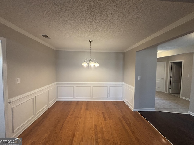 1365 Jubilee Ln, Mcdonough, GA 30253 - unfurnished dining area featuring visible vents, a wainscoted wall, wood finished floors, and a notable chandelier