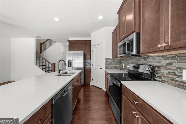 kitchen with dark wood finished floors, light countertops, a sink, decorative backsplash, and appliances with stainless steel finishes