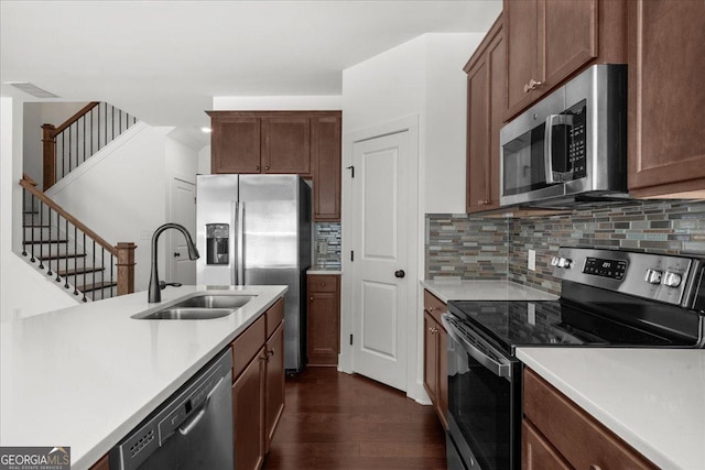 kitchen featuring tasteful backsplash, a sink, light countertops, appliances with stainless steel finishes, and dark wood-style floors