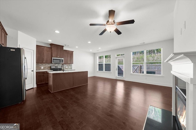unfurnished living room with a ceiling fan, baseboards, recessed lighting, and dark wood-type flooring