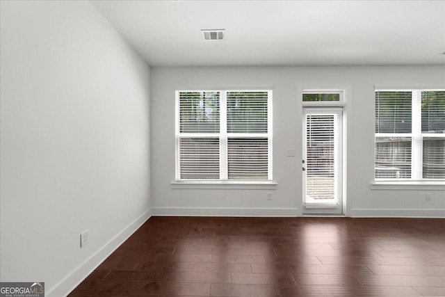 spare room featuring baseboards, dark wood-type flooring, and visible vents