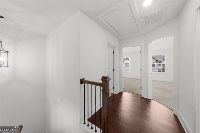 corridor featuring attic access, dark wood-type flooring, an upstairs landing, and visible vents