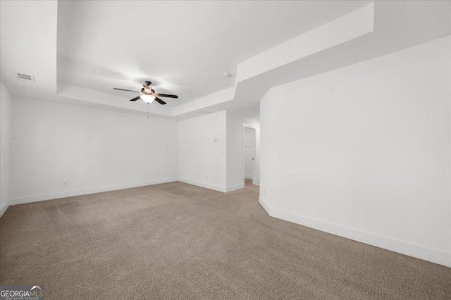 unfurnished room featuring a raised ceiling, baseboards, and ceiling fan