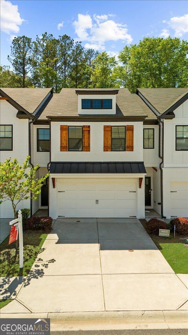 multi unit property with a garage, metal roof, a standing seam roof, and concrete driveway