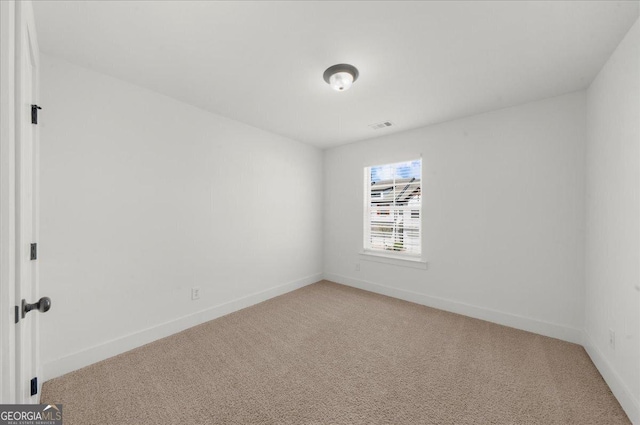 spare room with light carpet, visible vents, and baseboards