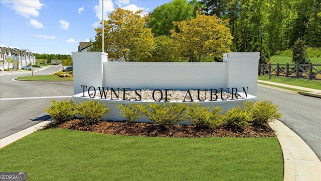 community / neighborhood sign featuring a lawn and fence